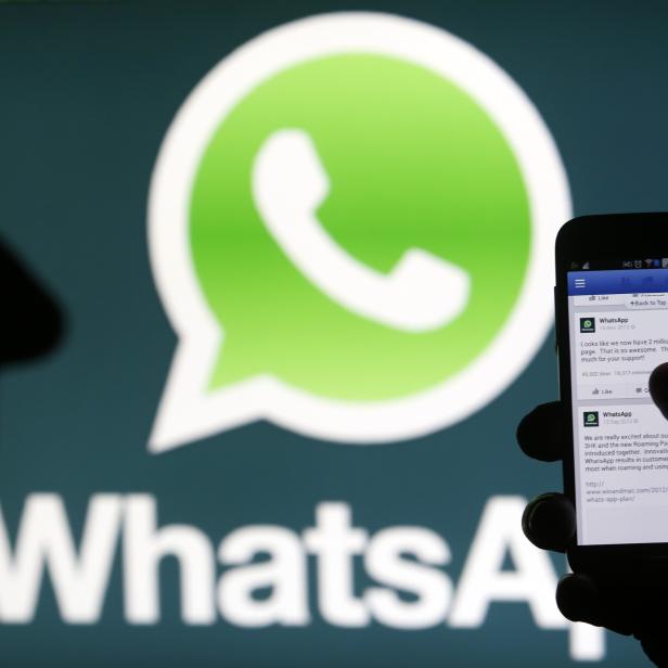 A Whatsapp App logo is seen behind a Samsung Galaxy S4 phone that is logged on to Facebook in the central Bosnian town of Zenica