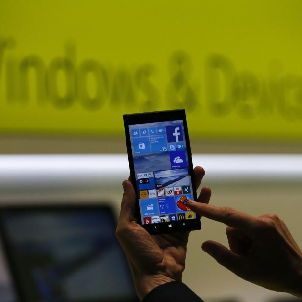 A Microsoft representative shows a smartphone with Windows 10 operating system at the CeBIT trade fair in Hanover in this file photo