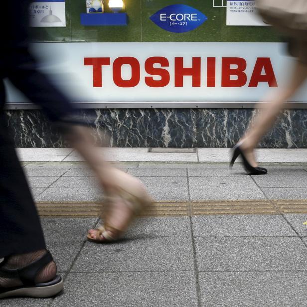 Pedestrians walk past a logo of Toshiba Corp outside an electronics retailer in Tokyo