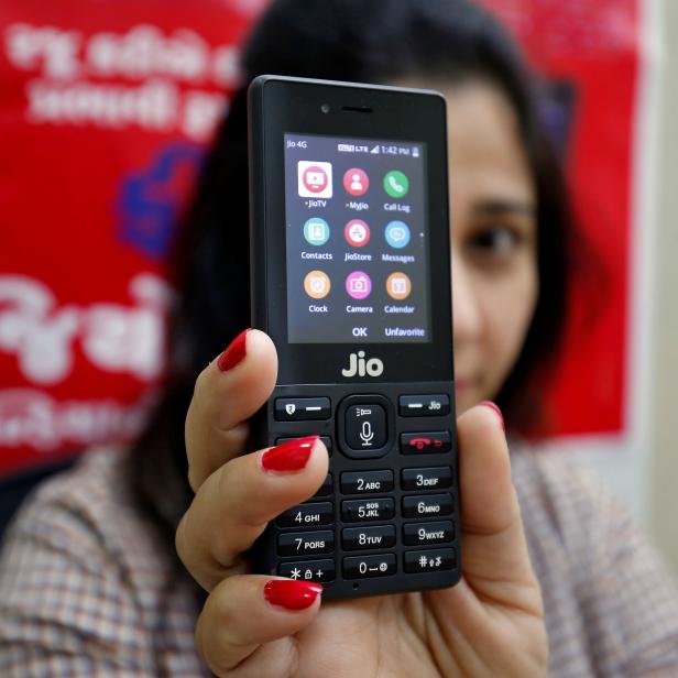 A sales person displays JioPhone as she poses for a photograph at a store of Reliance Industries' Jio telecoms unit, on the outskirts of Ahmedabad