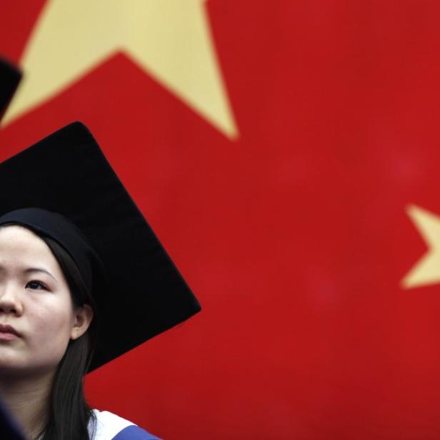 Eine junge Frau mit Doktorhut vor der chinesischen Flagge.