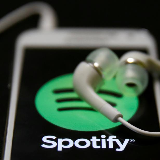 FILE PHOTO: Earphones are seen on top of a smart phone with a Spotify logo on it