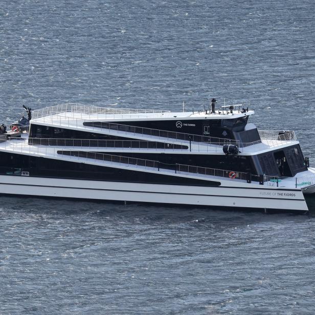 Ein schwarz-weißer Katamaran, „Future of the Fjords“, fährt auf dem Wasser.