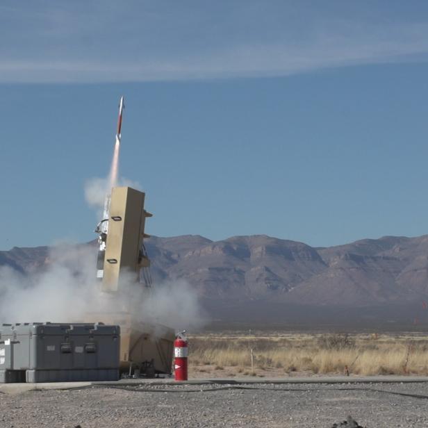 Eine Rakete startet von einer Abschussrampe in einer Wüstenlandschaft.