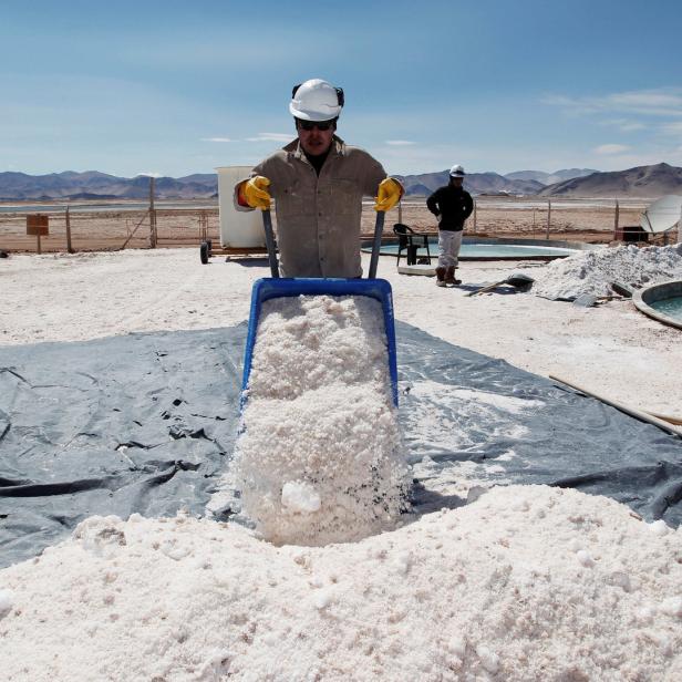 Ein Arbeiter schüttet Salz aus einer Schubkarre auf eine Plane.