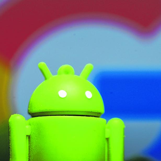 A 3D printed Android mascot Bugdroid is seen in front of a Google logo in this illustration