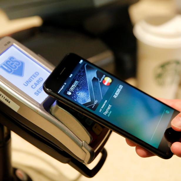 Man uses iPhone 7 smartphone to demonstrate mobile payment service Apple Pay at cafe in Moscow