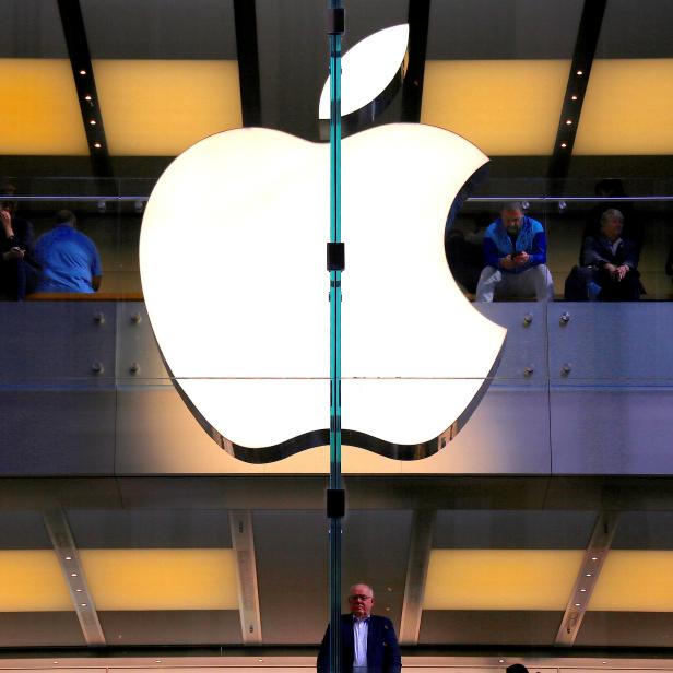 FILE PHOTO: A customer stands underneath an illuminated Apple logo as he looks out the window of the Apple store located in central Sydney