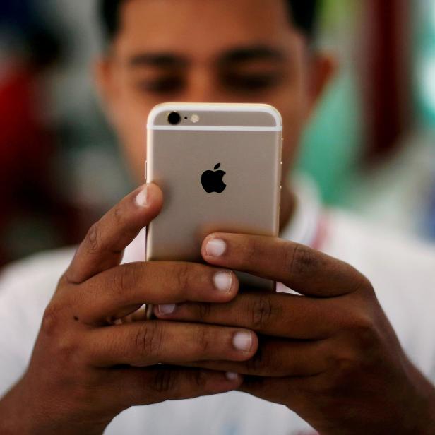 FILE PHOTO: A salesman checks a customer's iPhone at a mobile phone store in New Delhi