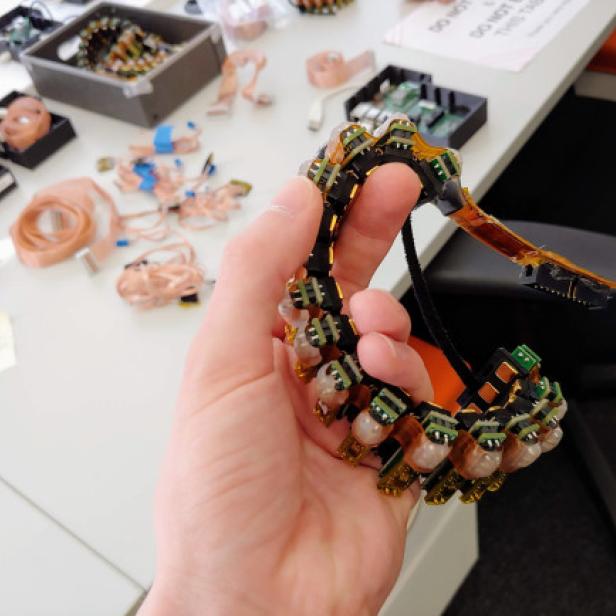 Eine Hand hält ein elektronisches Armband mit Sensoren.