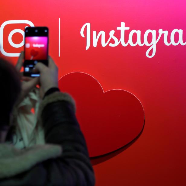 FILE PHOTO: A visitor takes a picture of the Instagram application logo at the Young Entrepreneurs fair in Paris