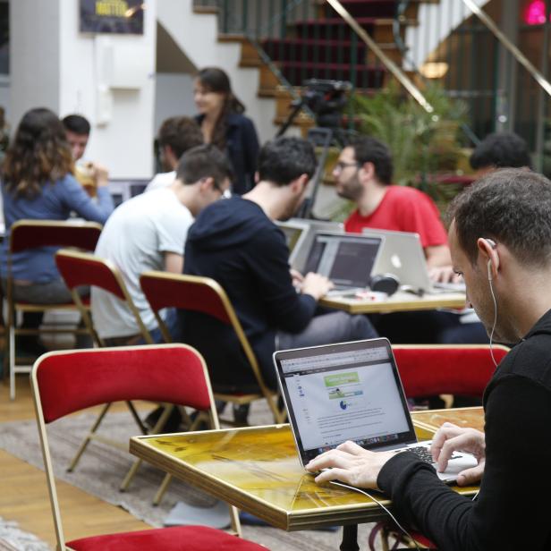 Entrepreneurs work at their computer laptops at the so-called "incubator" of French high-tech start-ups "TheFamily" in Paris