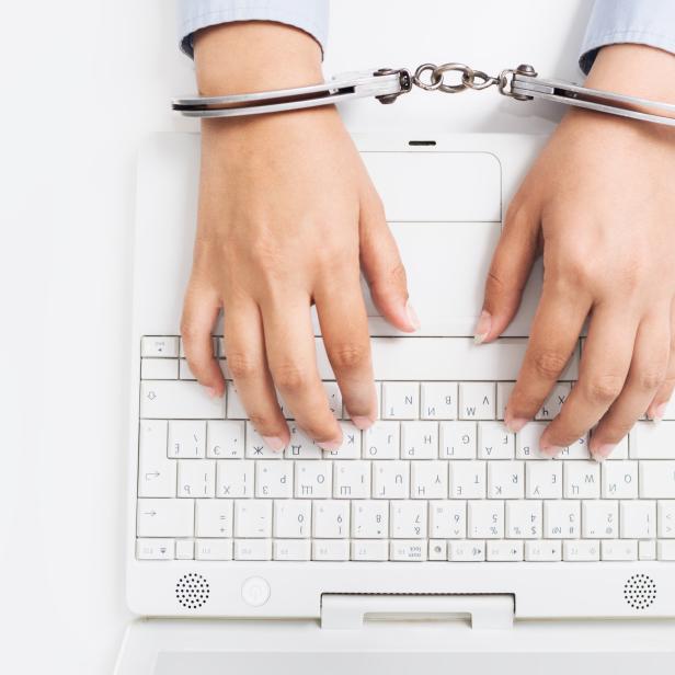 Female hands handcuffed to white keyboard