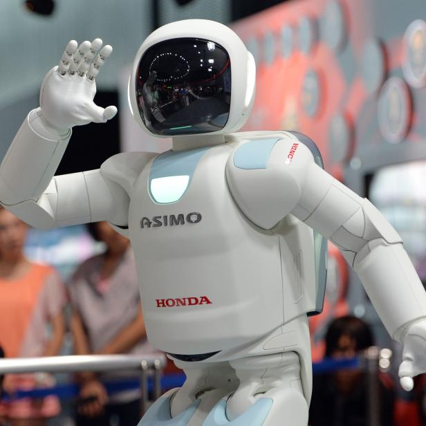 Der Honda-Roboter ASIMO winkt in die Kamera.