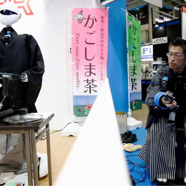 A tea master operates SEED Solutions' platform robot SEED-Noid by remote control as it roasts tea leaves during its demonstration at Robot Development & Application Expo in Tokyo