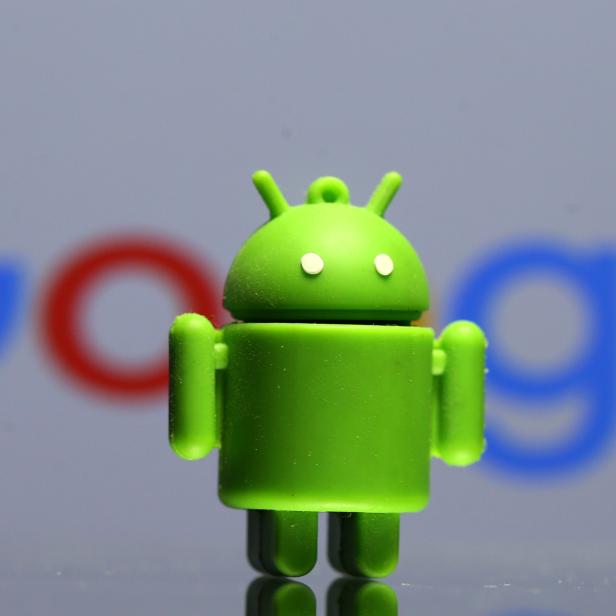 A 3D printed Android mascot Bugdroid is seen in front of a Google logo in this illustration