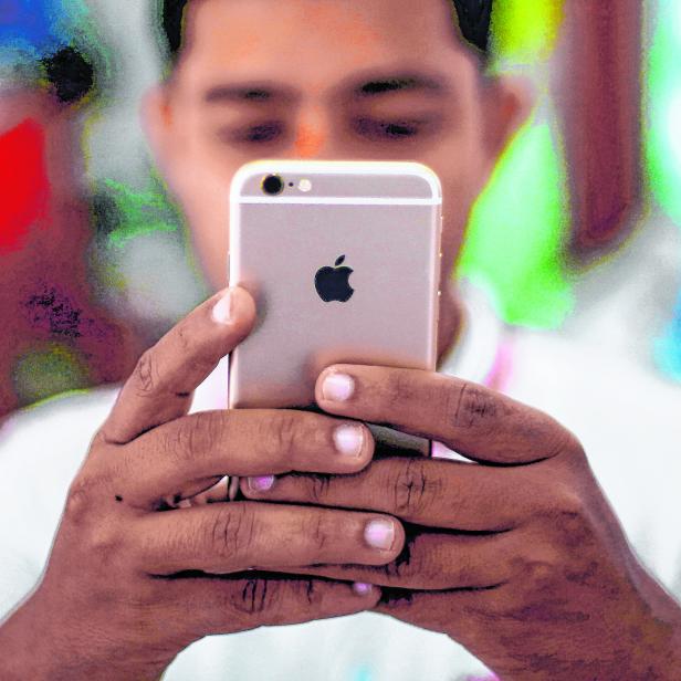 FILE PHOTO: A salesman checks a customer's iPhone at a mobile phone store in New Delhi