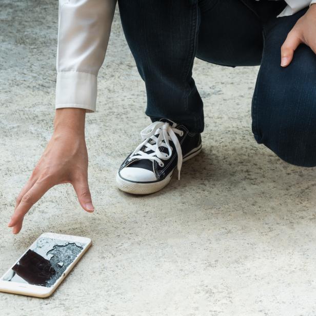 Person Picking Broken Smart Phone of Ground