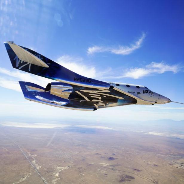 Das Raumschiff „Virgin Galactic“ fliegt über eine Wüstenlandschaft.