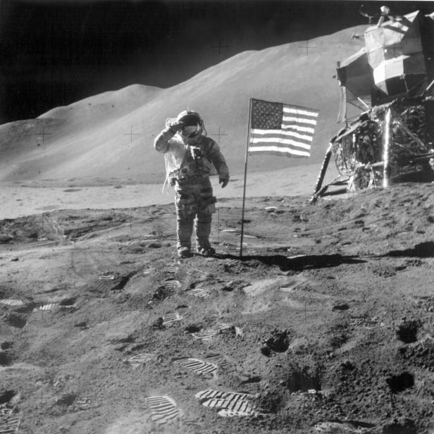 Ein Astronaut salutiert auf dem Mond neben der amerikanischen Flagge und der Mondlandefähre.