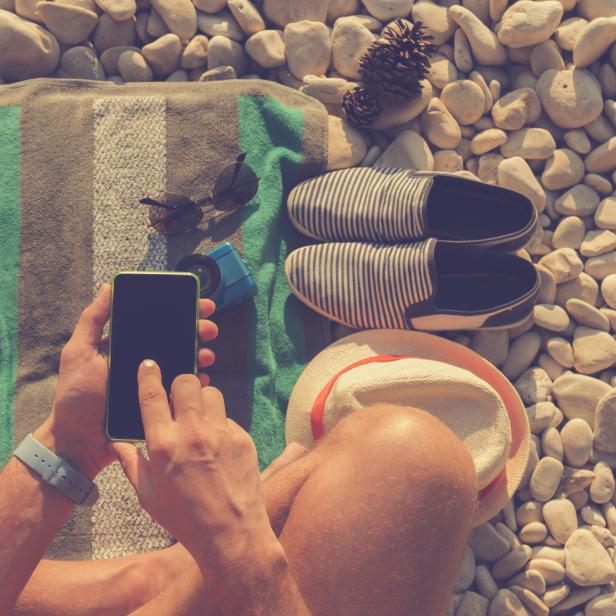 Man using cellphone on the beach.