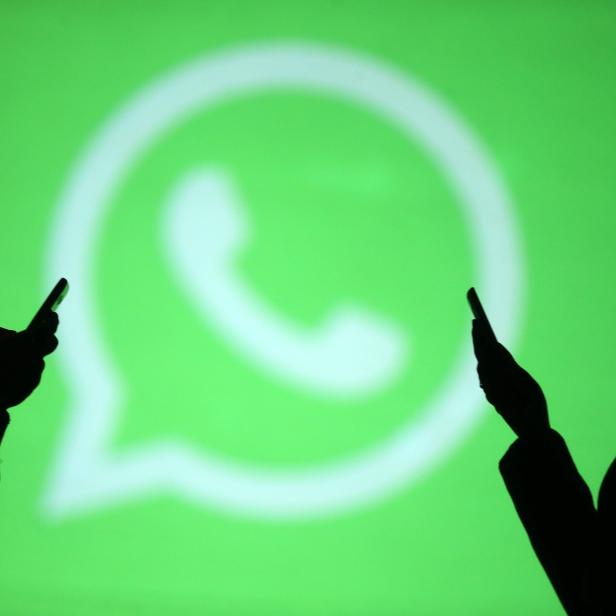 Silhouettes of mobile users are seen next to a screen projection of Whatsapp logo in this picture illustration