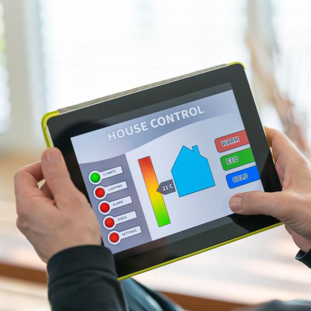 Ein Mann bedient ein digitales Tablet zur Steuerung seines Hauses.