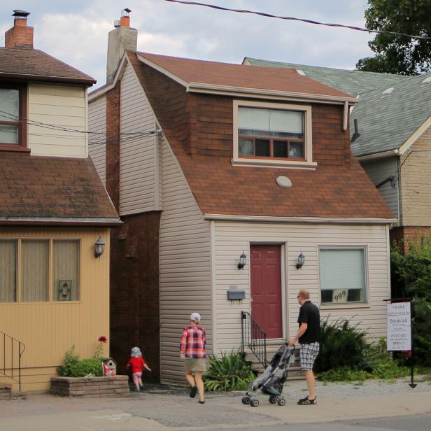 FILE PHOTO: A family passes a house for sale on Mount Pleasant Road in Toronto