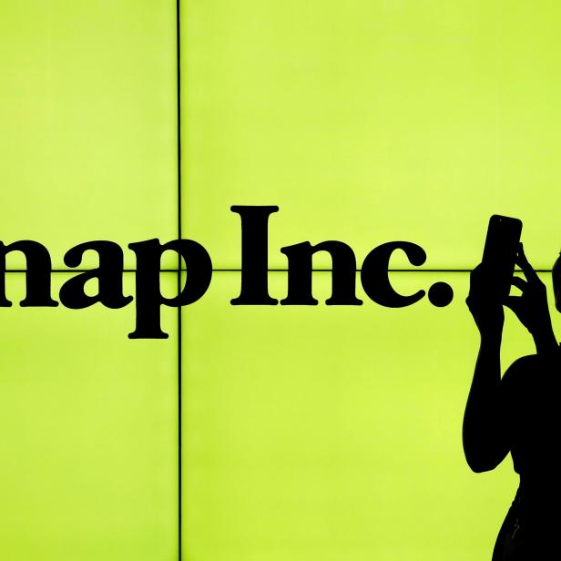 FILE PHOTO - A woman stands in front of the logo of Snap Inc. on the floor of the New York Stock Exchange in New York City