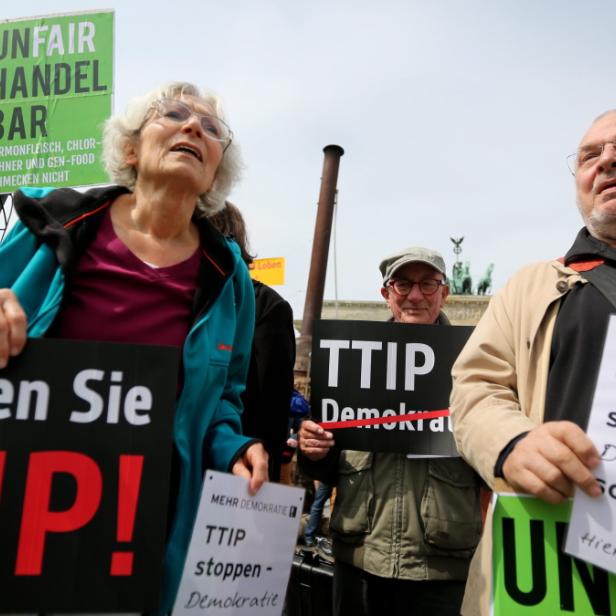 Menschen demonstrieren gegen TTIP mit Schildern vor dem Brandenburger Tor.