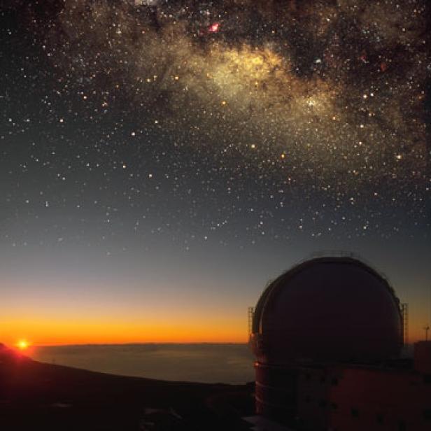 Ein Observatorium unter einem sternenklaren Nachthimmel mit der Milchstraße im Hintergrund.