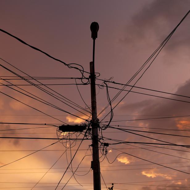 A street light post and power lines are seen at sunset during a blackout in Maracaibo