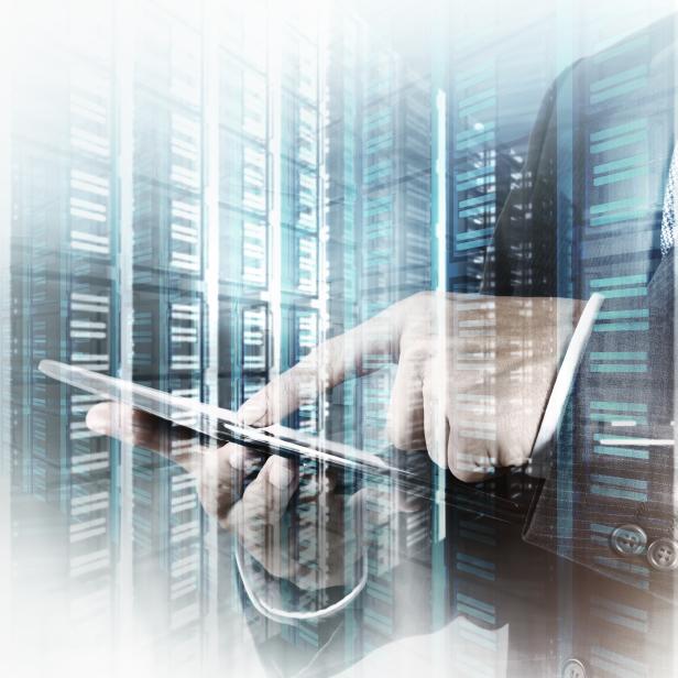 Ein Mann im Anzug bedient ein Tablet vor einem Hintergrund aus Server-Racks.