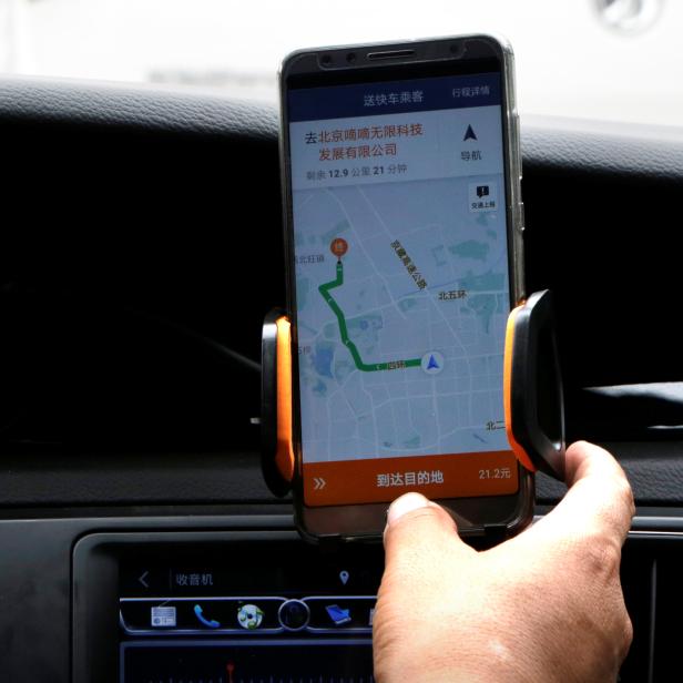 A Didi Chuxing driver checks the information on the application in his car in Beijing