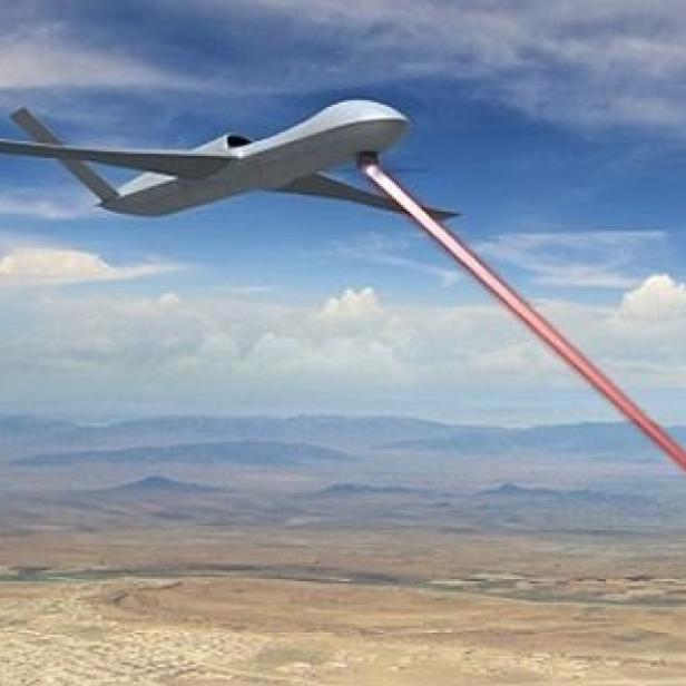 Eine Drohne sendet einen roten Laserstrahl über eine Wüstenlandschaft.