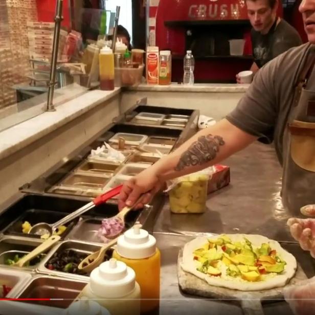 Ein Koch bereitet eine Pizza mit frischen Zutaten zu.