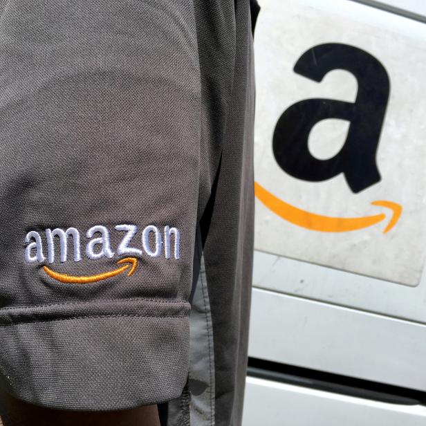 FILE PHOTO: FILE PHOTO: An Amazon.com Inc driver stands next to an Amazon delivery truck in Los Angeles, California