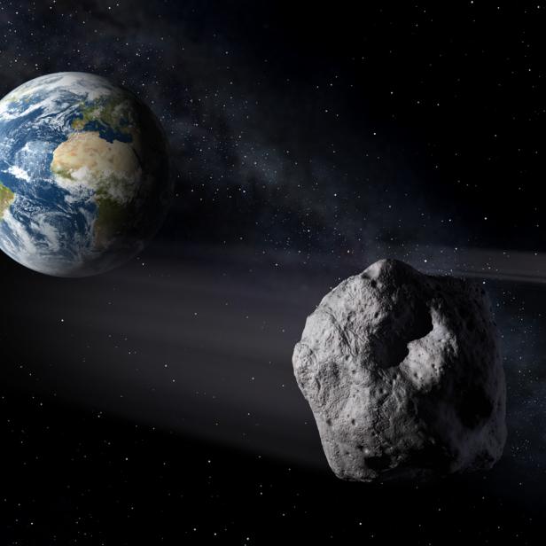 Ein Asteroid und sein kleinerer Begleiter sind vor der Erde im Weltraum zu sehen.