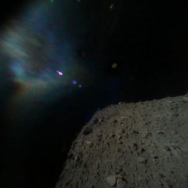 Die Oberfläche eines Asteroiden im Weltraum mit Lichtreflexionen.