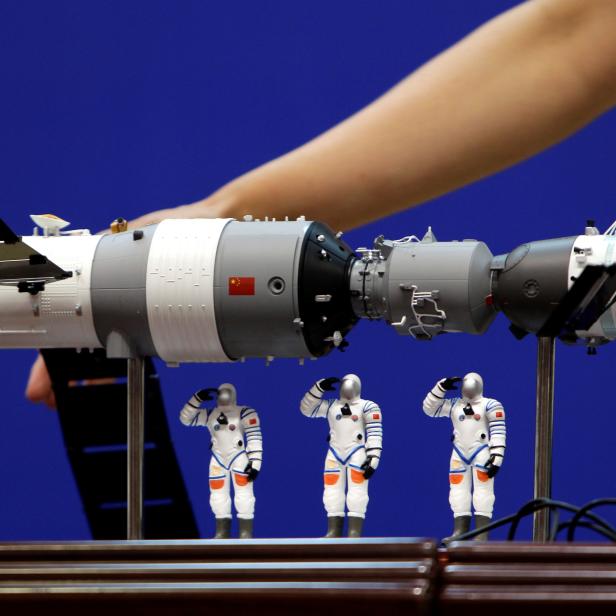 FILE PHOTO: A model of the Tiangong-1 space lab module, the Shenzhou-9 manned spacecraft and three Chinese astronauts is displayed during a news conference