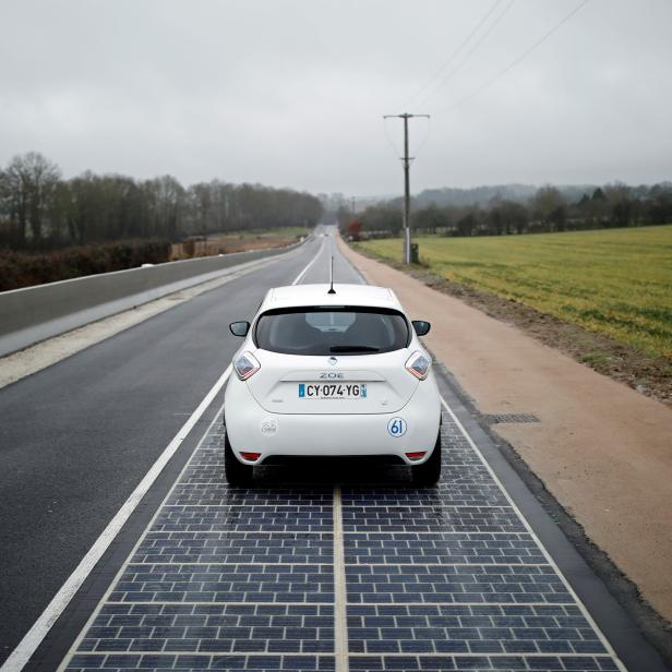 An automobile drives on a solar panel road during its inauguration in Tourouvre