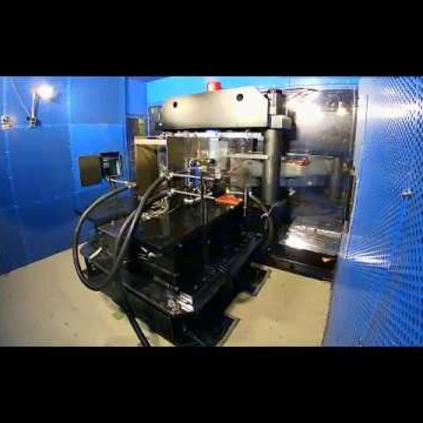 Ein großer, schwarzer Hydraulikzylinder steht in einem blauen Raum.