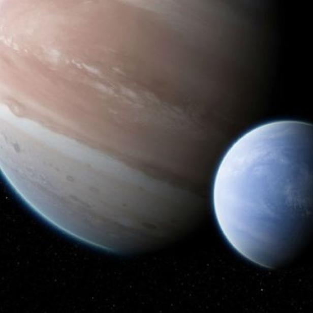 Ein großer, beiger Planet und ein kleinerer, blauer Planet vor einem Sternenhintergrund.