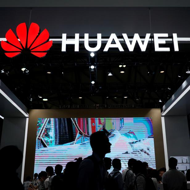 People walk past a sign board of Huawei at CES (Consumer Electronics Show) Asia 2018 in Shanghai