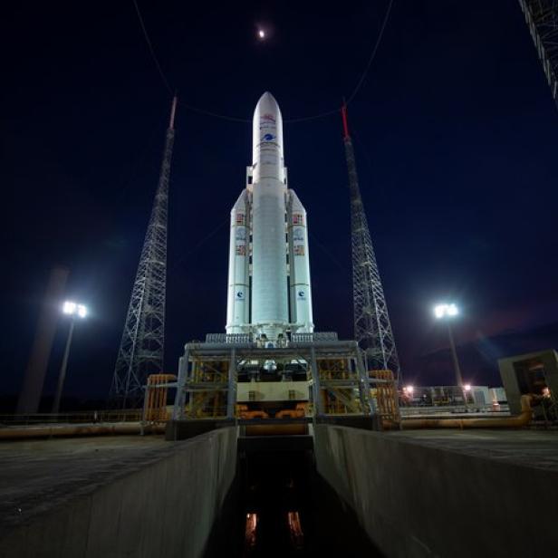 Eine Ariane-5-Rakete steht nachts auf einer Startrampe unter einem dunklen Himmel.