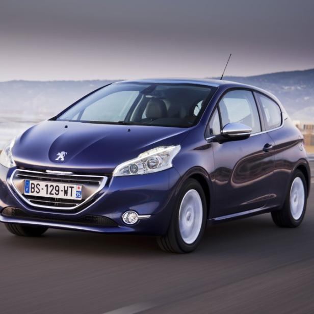 Ein blauer Peugeot 208 fährt auf einer Küstenstraße.