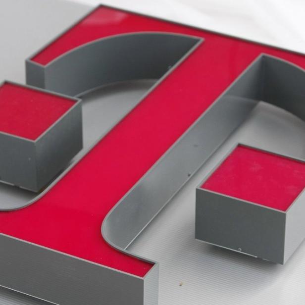 Ein großes, dreidimensionales „T“ in Grau und Rot liegt auf einer Oberfläche.