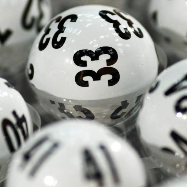 Mehrere weiße Lottokugeln mit schwarzen Zahlen liegen nebeneinander.