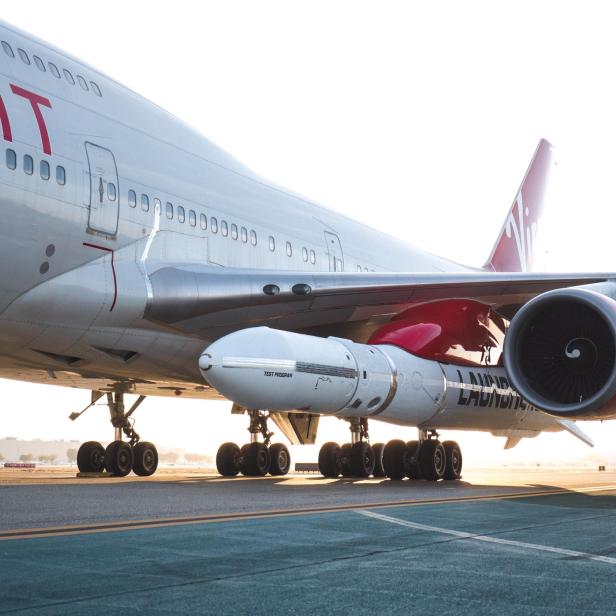 Ein Virgin Orbit Flugzeug mit einer Rakete unter dem Flügel auf einer Startbahn.