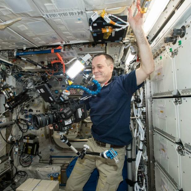 Ein Astronaut in der Internationalen Raumstation (ISS) mit einer professionellen Kamera.